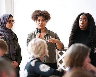 Young woman holds microphone to speak to group