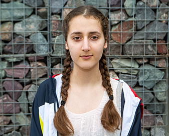 Young woman in front of a stone wall