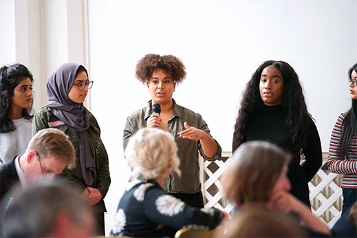 Young woman holds microphone while speaking to a group