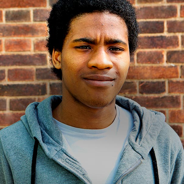 Young man in front of a red brick wall