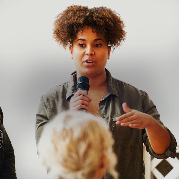Young woman holds a microphone whilst speaking to a group