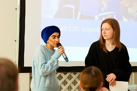 Woman holds microphone whilst giving a presentation