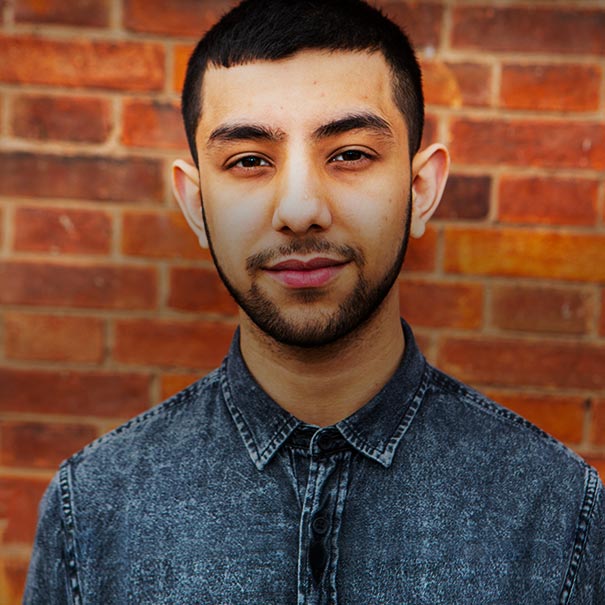 Young man in front of a red brick wall