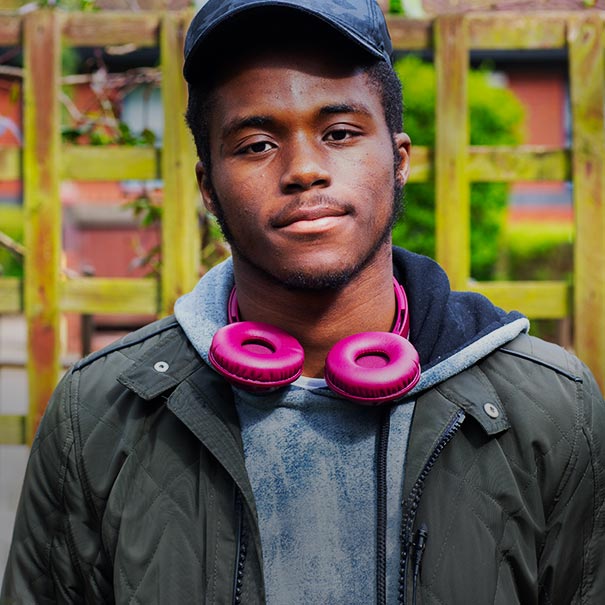 Young man with pink headphones in a garden