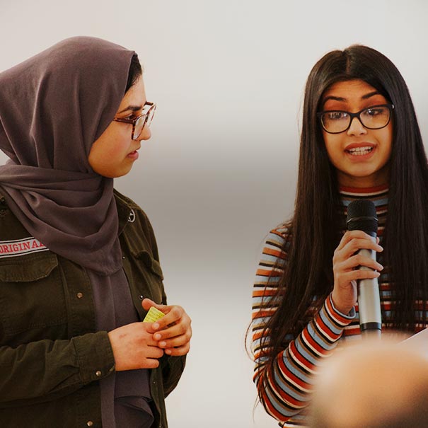 Young woman holds a microphone whilst speaking to a group